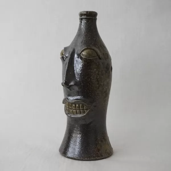 full view image of a sculpture of a face in the shape of a coke bottle